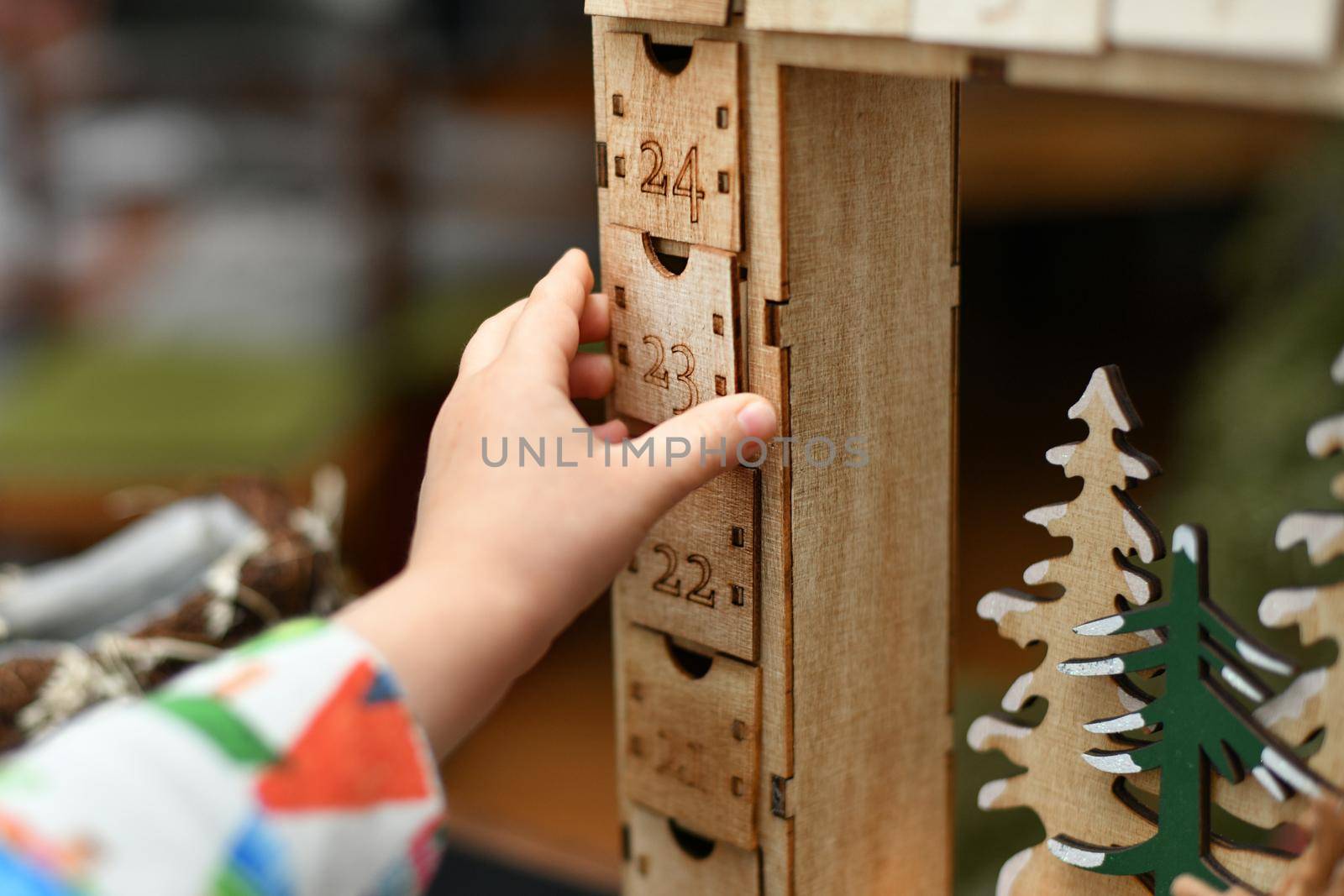 A child opens wooden advent calendar with presents by Godi