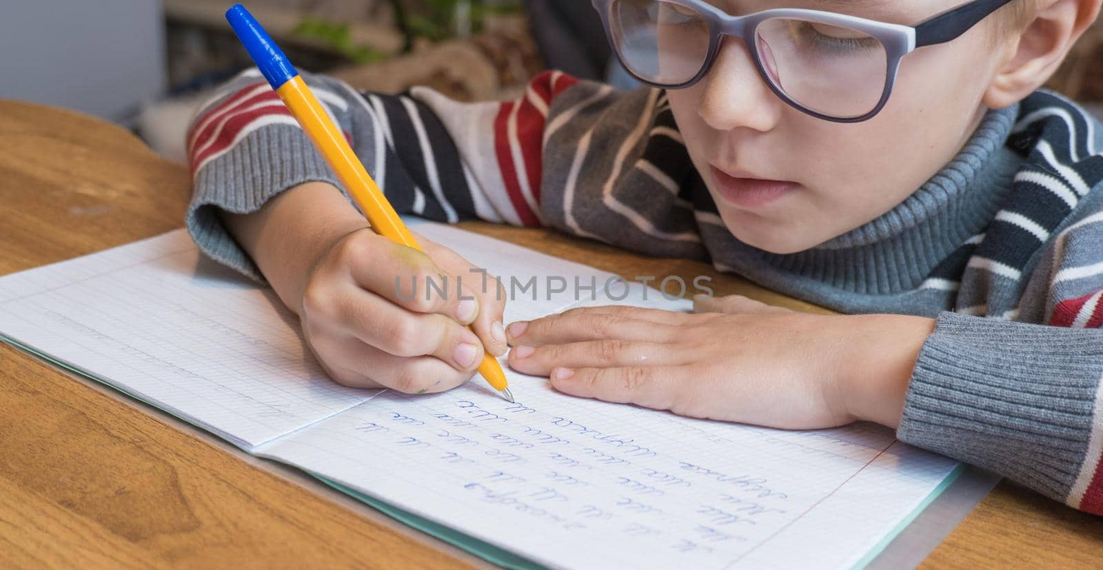 Focused first grader learning to write and doing homework by Ekaterina34