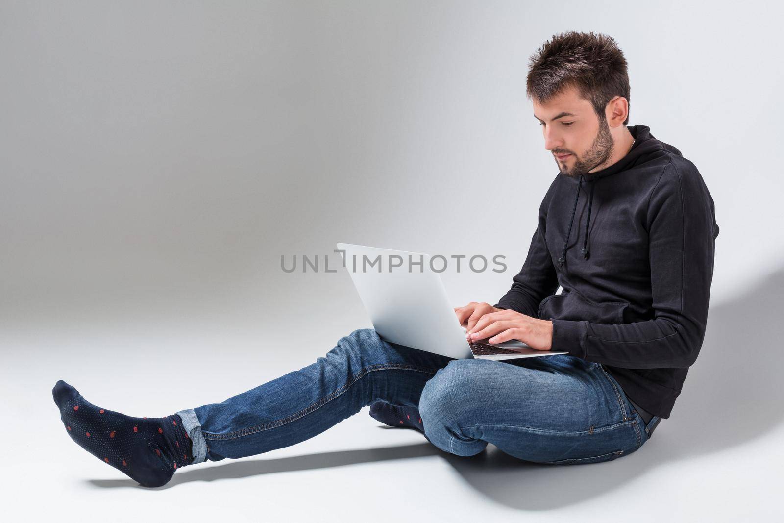a young man in casual clothes working on a laptop.