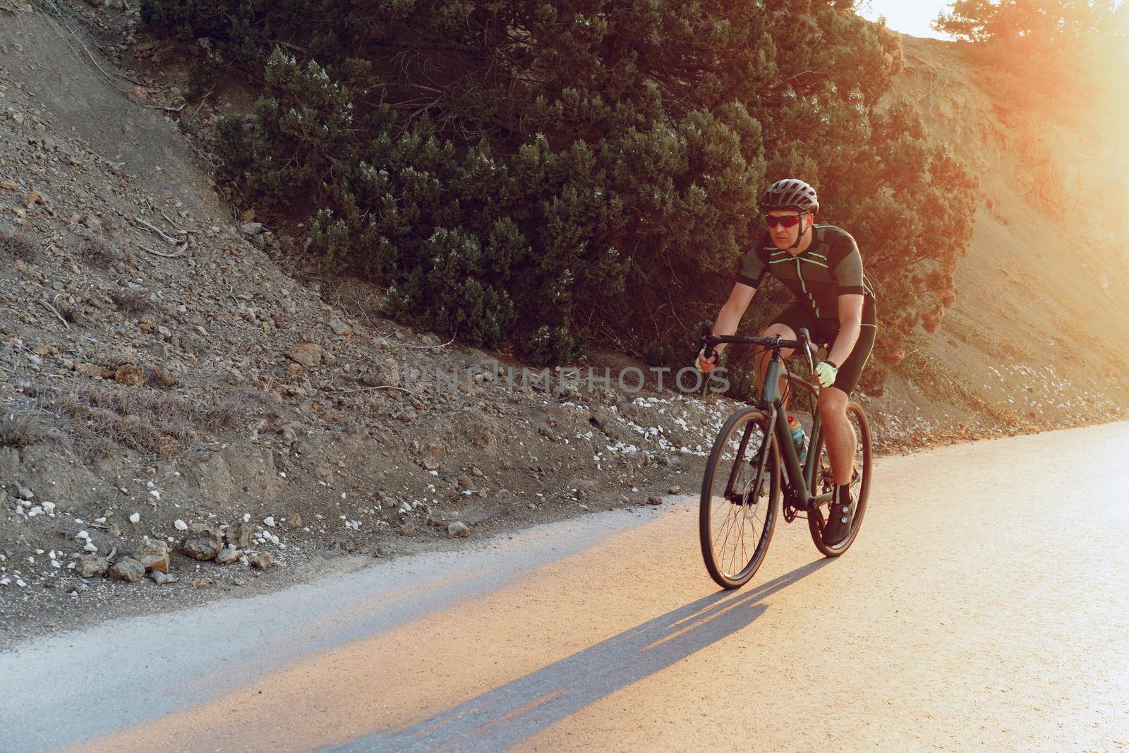 Professional man cyclist on a mountain road at sunrise