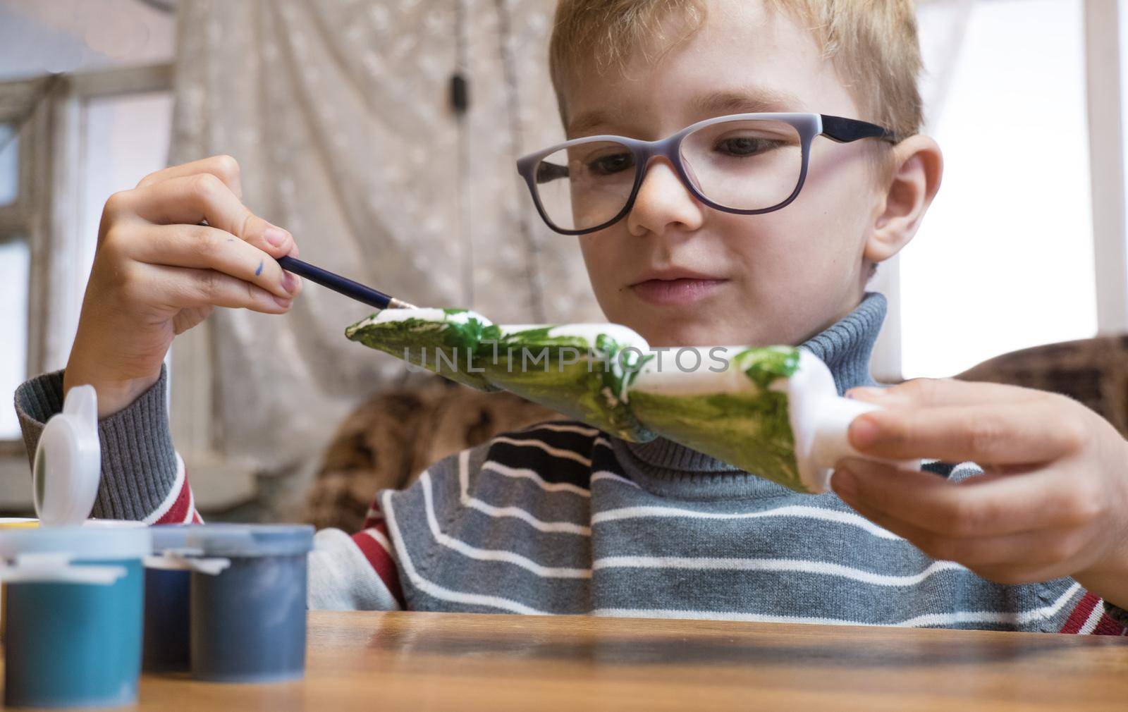 A seven-year-old boy paints a Styrofoam Christmas tree green in preparation for Christmas. Handmade Christmas Gift Ideas. by Ekaterina34