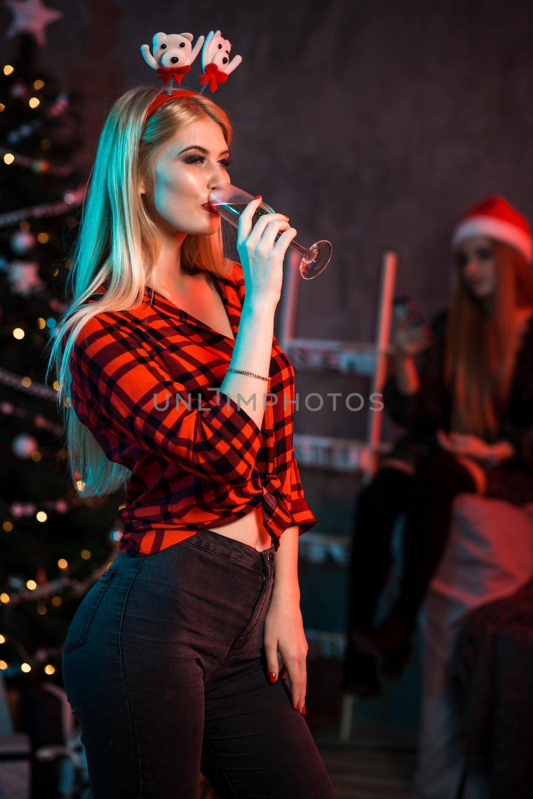 Beautiful young woman with glass of champagne at Christmas party by nazarovsergey