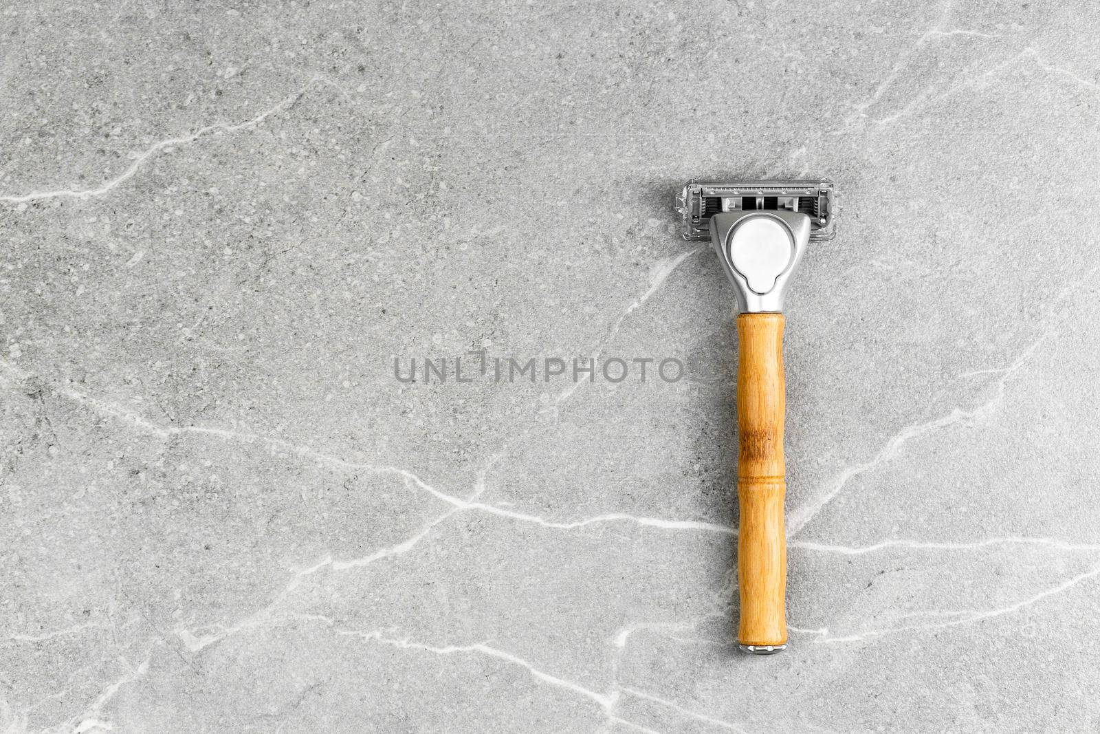 Shaving Razor with wooden handle on a grey marble background. Plastic free hygiene tool. Free space for branding