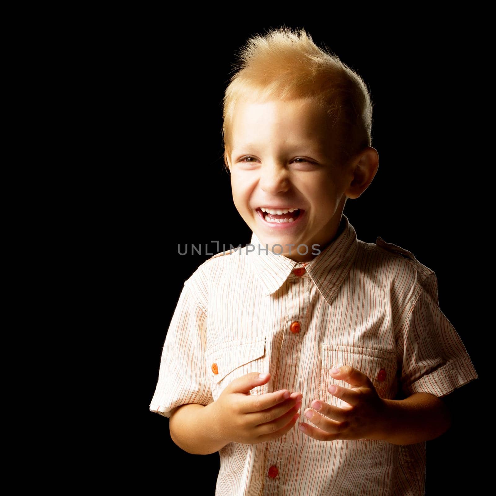 Beautiful little boy closeup. Studio portrait on black background. Concept layout for magazine cover.