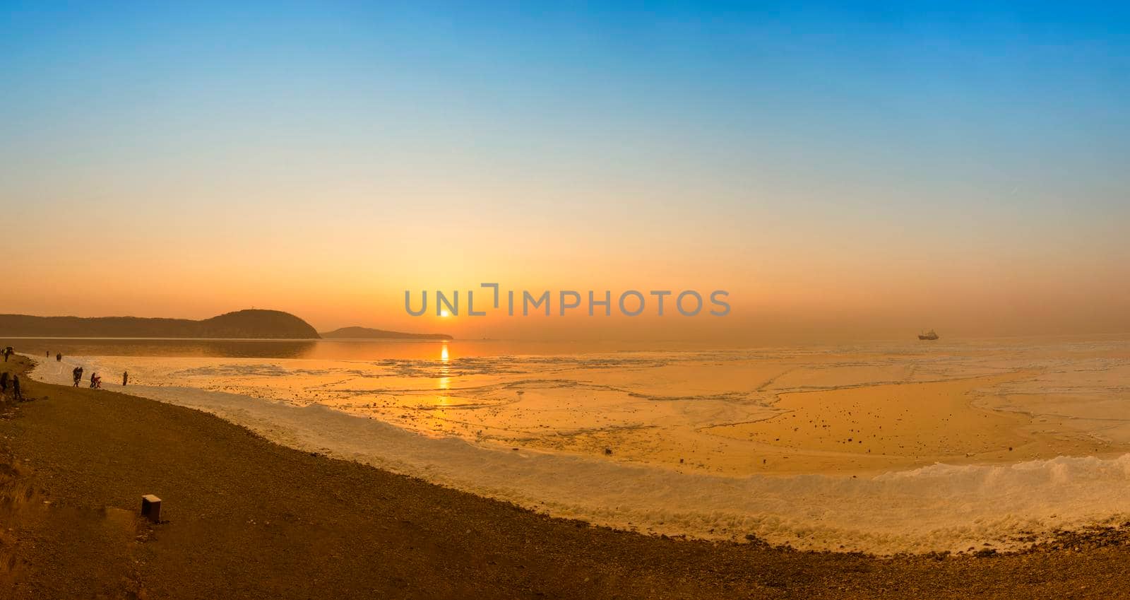 Panorama of the sea landscape with a view of the sunset over the ice surface.