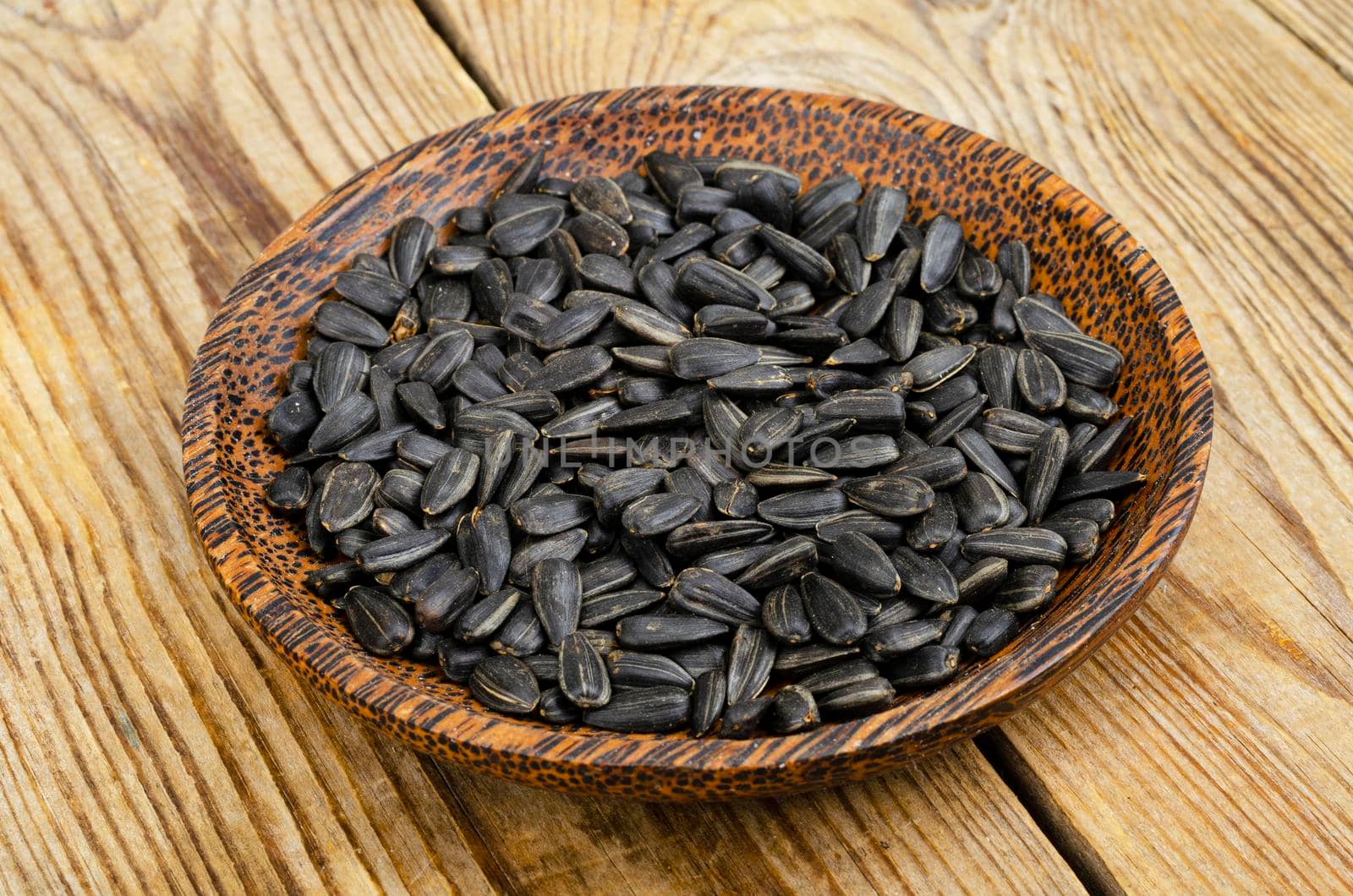 Bowl with sunflower seeds on wooden background. by ArtCookStudio
