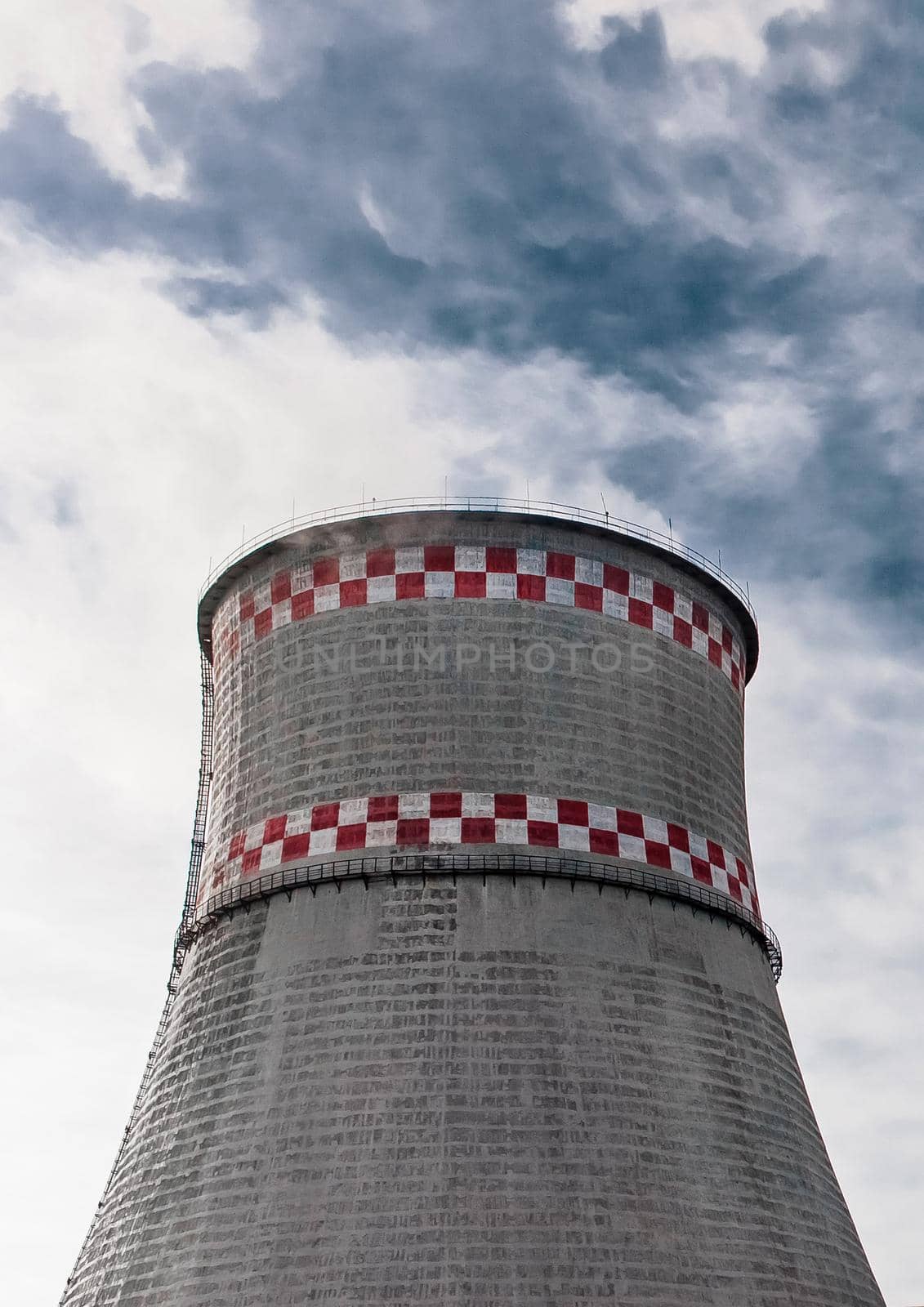 Cooling tower of an industrial plant or thermal power plant against a blue sky by AYDO8