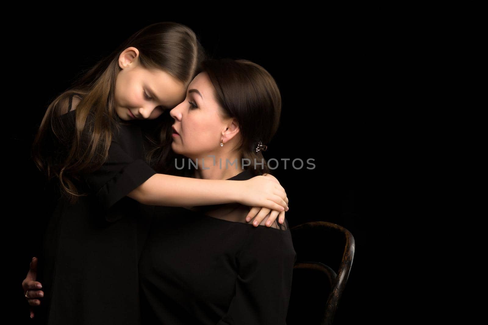 Happy family mom and daughter in the studio on a black background. The concept of love, childhood.