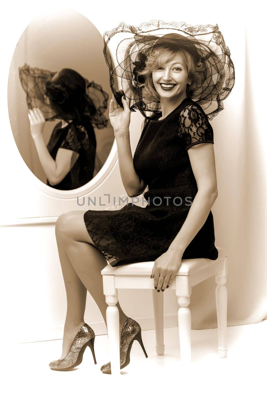 Stylish young woman in a luxurious hat near the mirror. The concept of beauty and fashion.