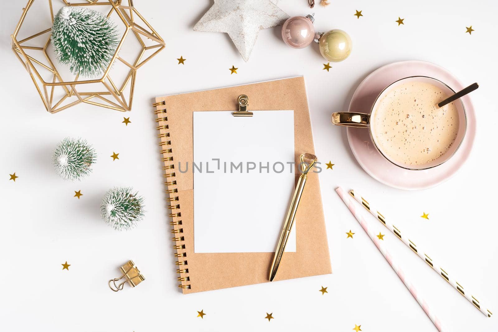 Desktop blank note pad. Flat lay of white working table background with cup of coffee and Christmas decoration. Top view balls, fir tree, paper clips, mock up greeting card, craft Notebook and pen.