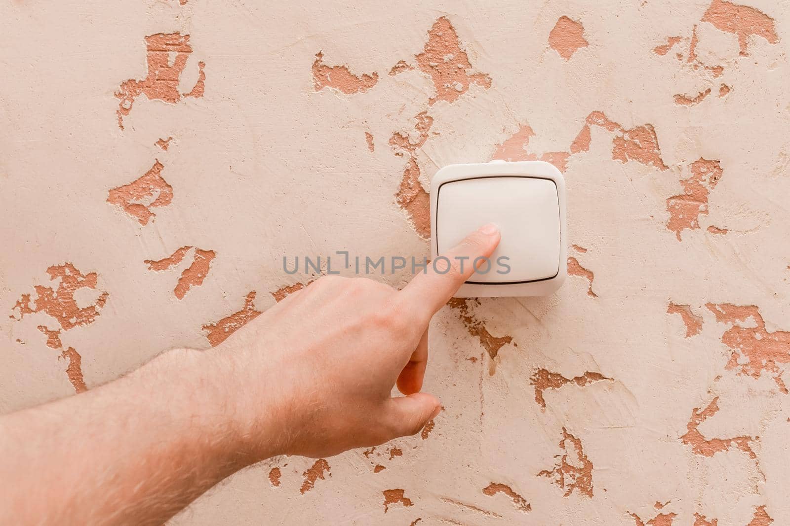 The guy's hand turns off the light with an electric switch in a modern room interior background.
