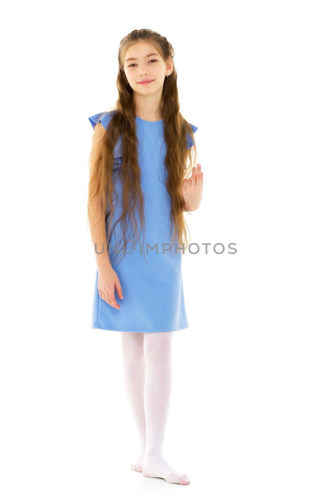 A charming little school girl corrects her long silky hair with her hands. The concept of style and fashion, happy people. Isolated on white background.