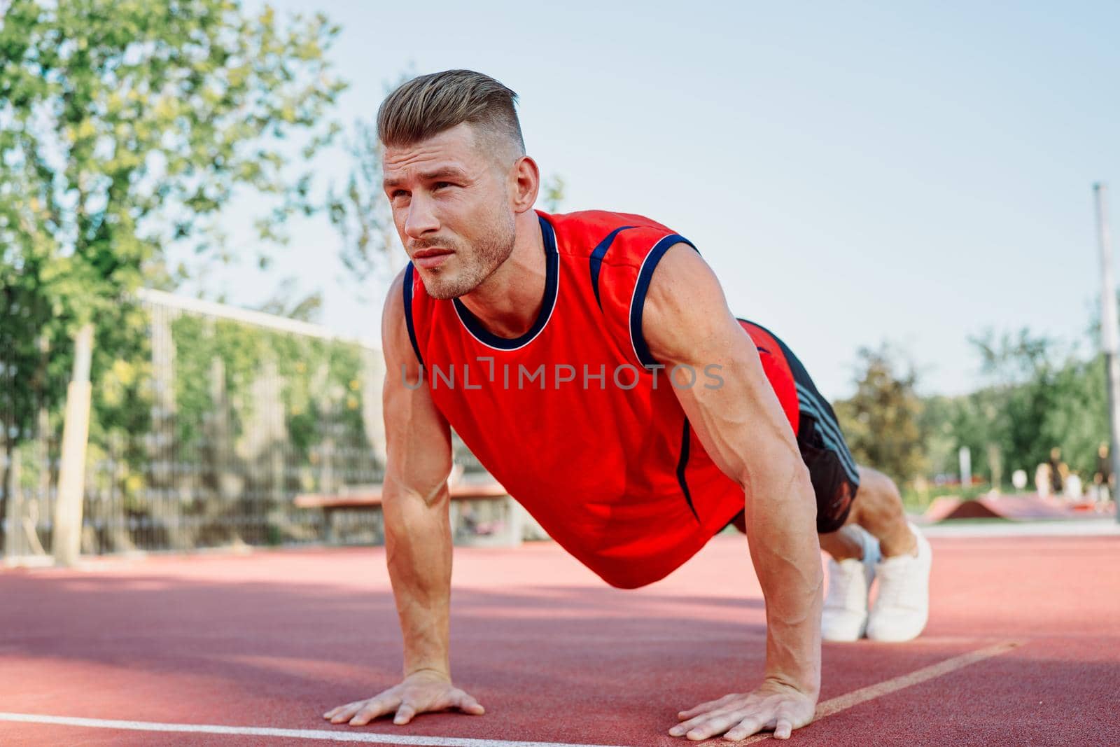 Muscled athletic men on the sports ground workout exercises by Vichizh