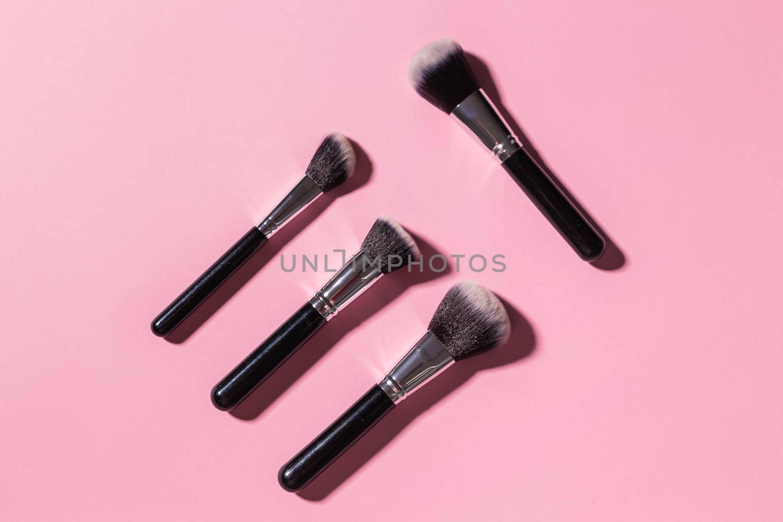 Various make-up brushes on pink background, top view. Cosmetics and beauty