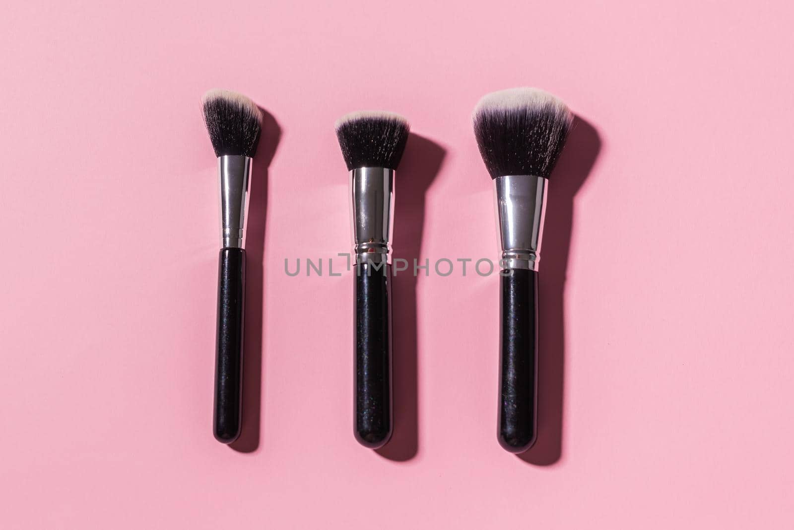 Various make-up brushes on pink background, top view. Cosmetics and beauty