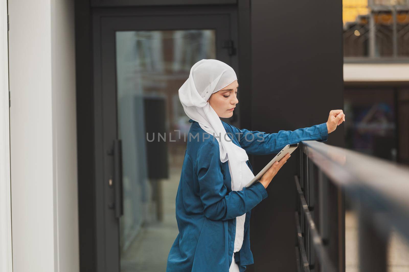 Young asian muslim woman in head scarf smile with mobile tablet and copy space by Satura86