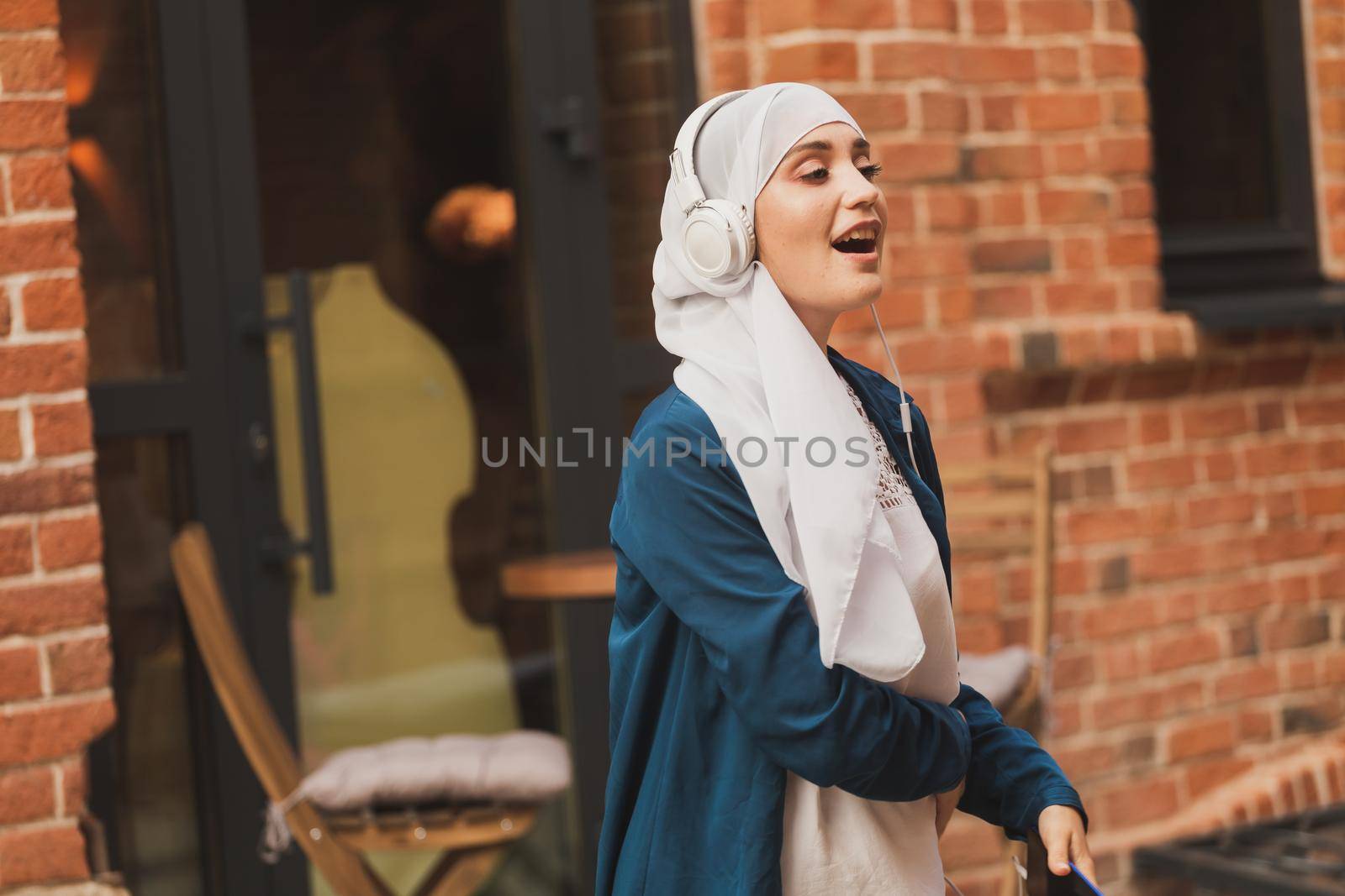 Portrait of young arabian muslim woman listening music with headphone and dancing. Feminism, woman independence and leisure concept