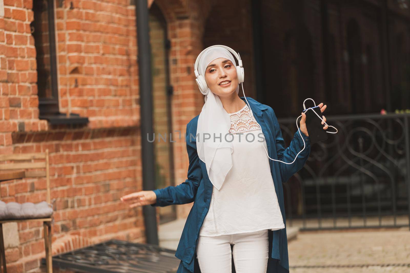 Portrait of young arabian muslim woman listening music with headphone and dancing. Feminism, woman independence and leisure concept
