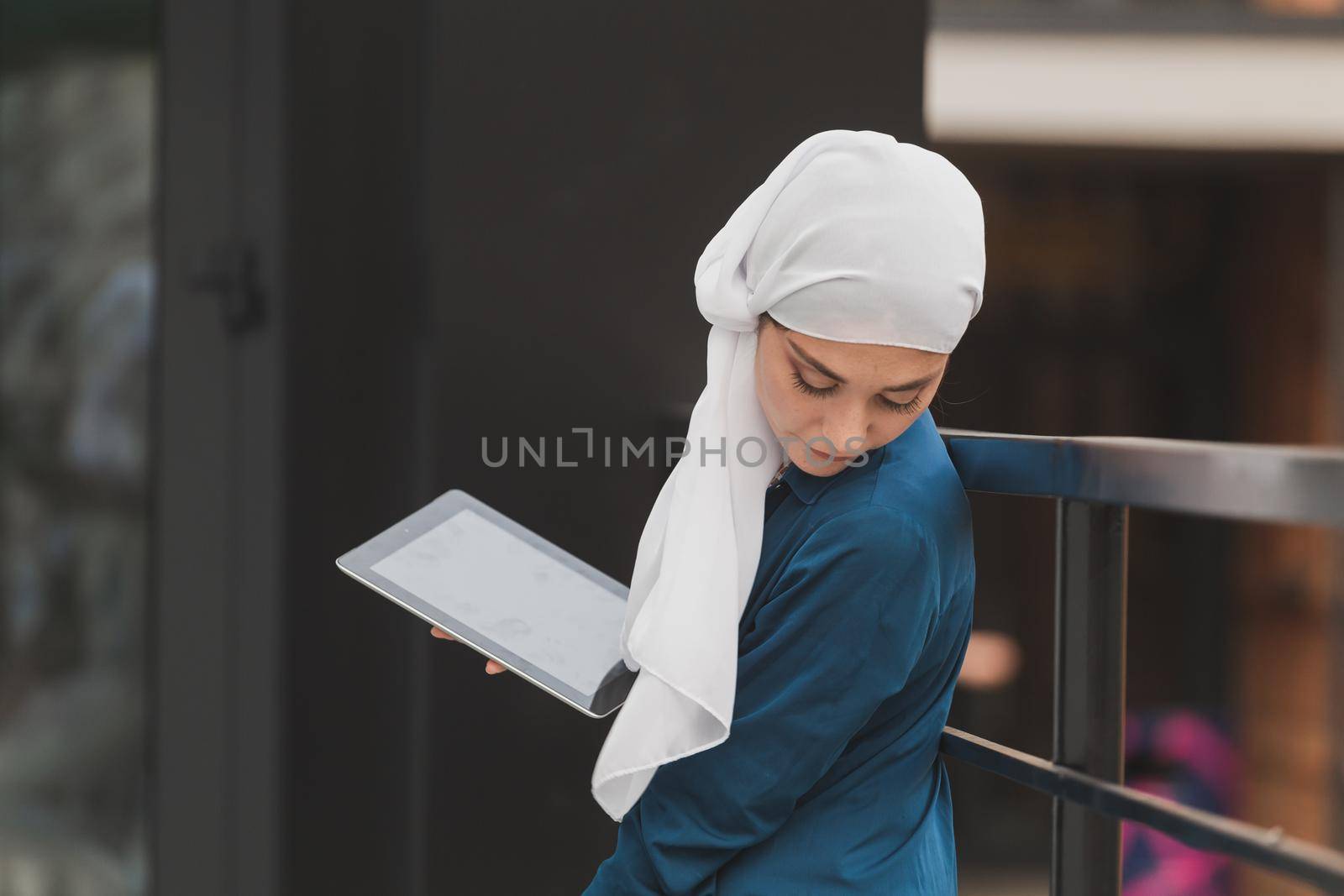 Beautiful muslim girl using digital tablet for communication with friend outdoor by Satura86