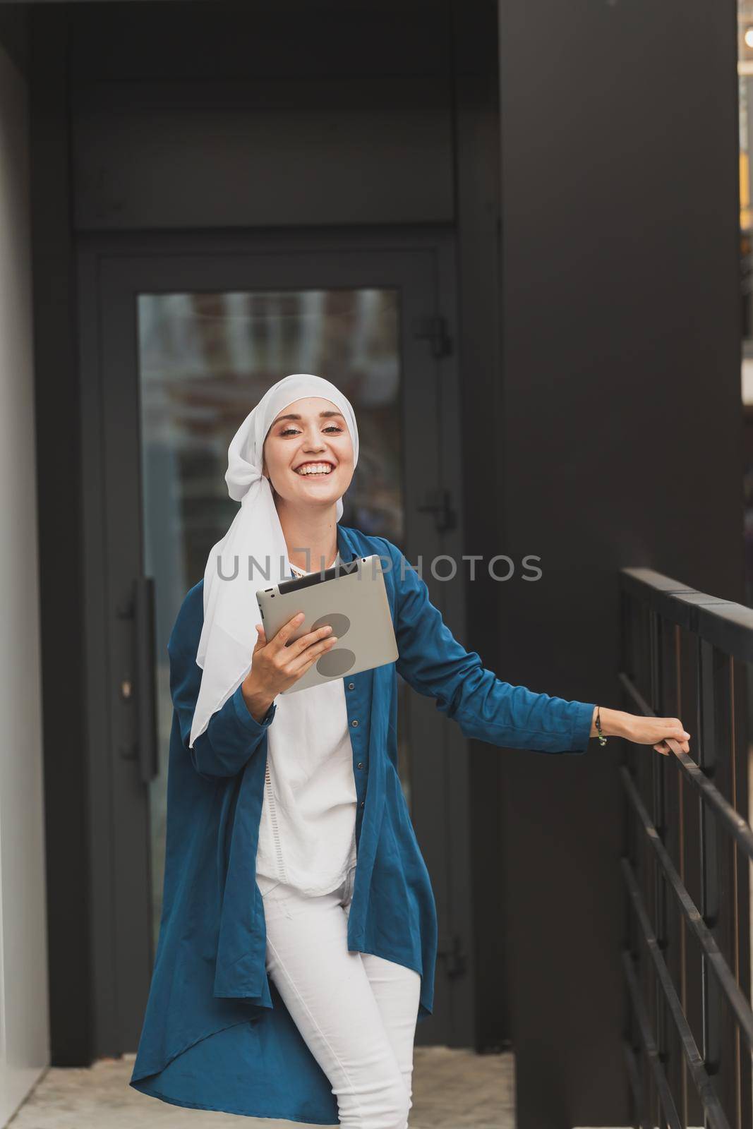 Beautiful muslim girl using digital tablet for communication with friend outdoor.