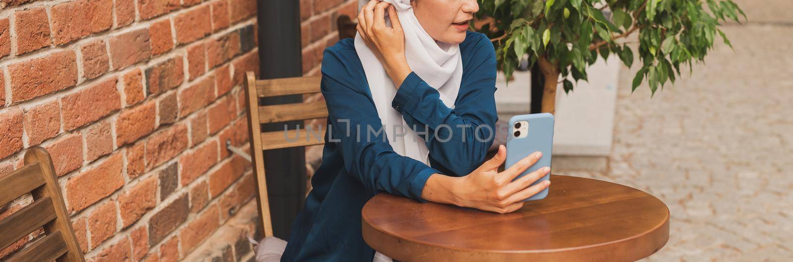 Happy muslim woman having video call on smartphone in city.