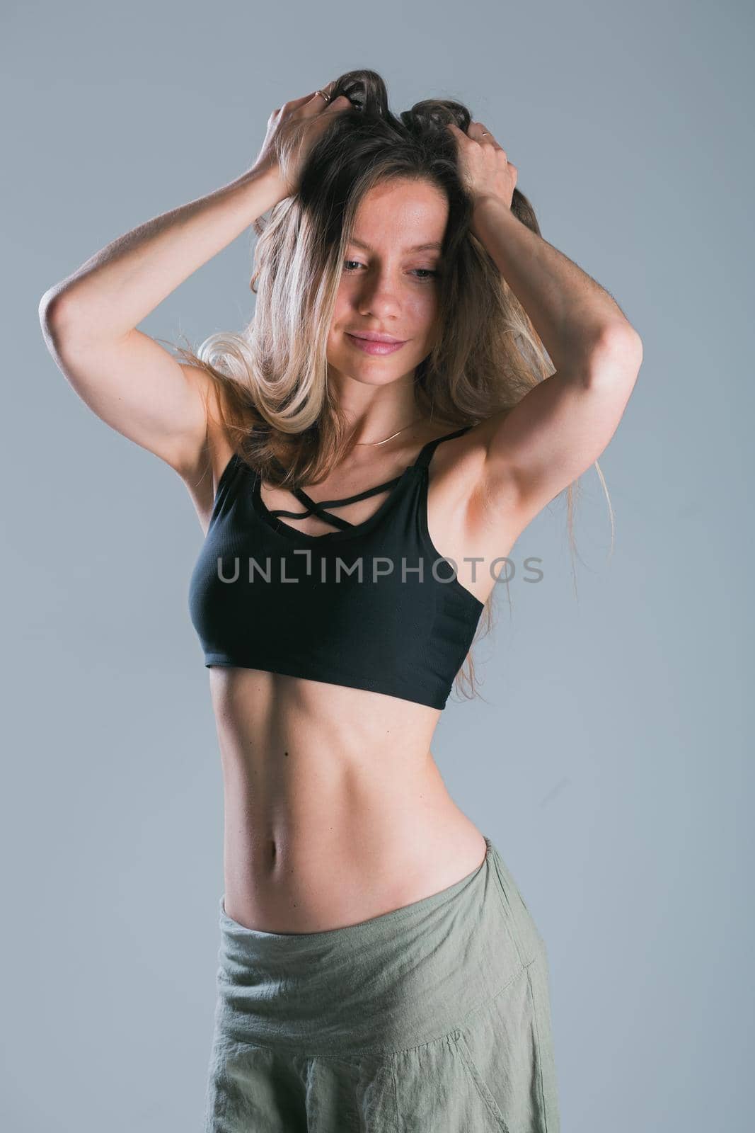 Fitness and diet concept. Portrait of young woman with perfect sporty body and pretty flat abs in sexy sportswear top on gray background. by Satura86