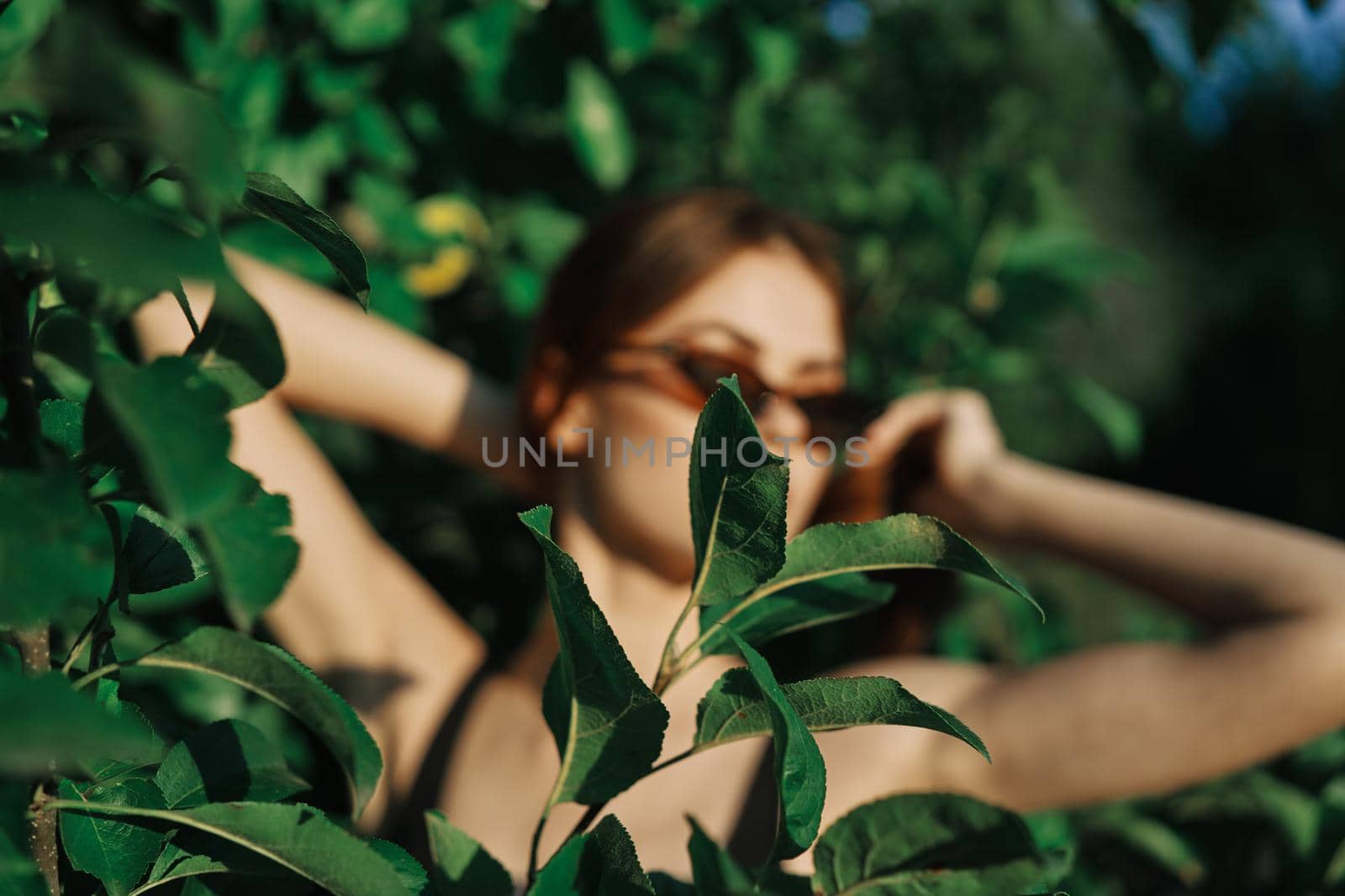 cheerful fashionable woman in sunglasses and green leaves summer luxury. High quality photo