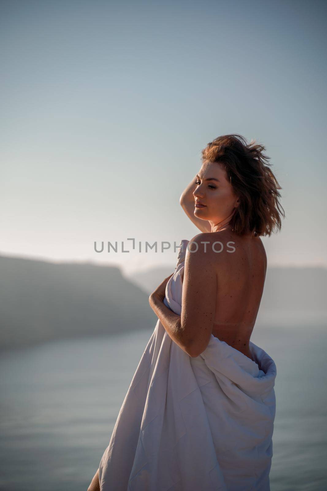 Woman wake up in bed wuth duvet and pillow over nature sea background outdoors. Back view. Good morning. Freedom concept. by Matiunina