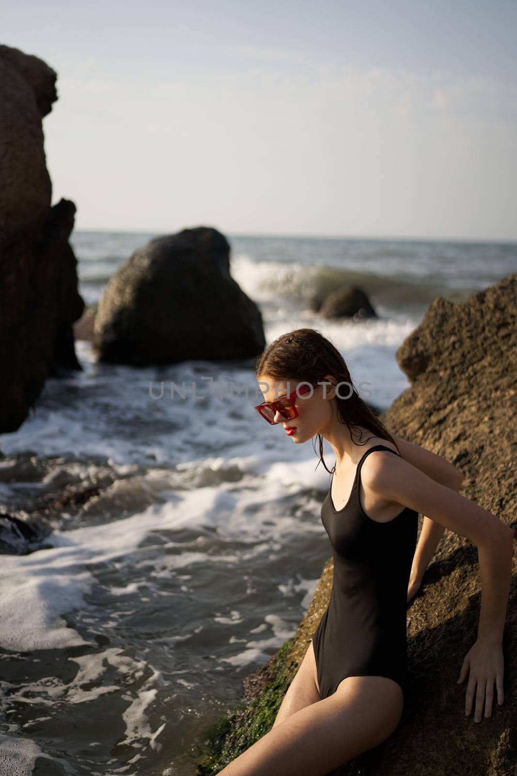 woman in swimsuit sunglasses ocean rocks posing. High quality photo