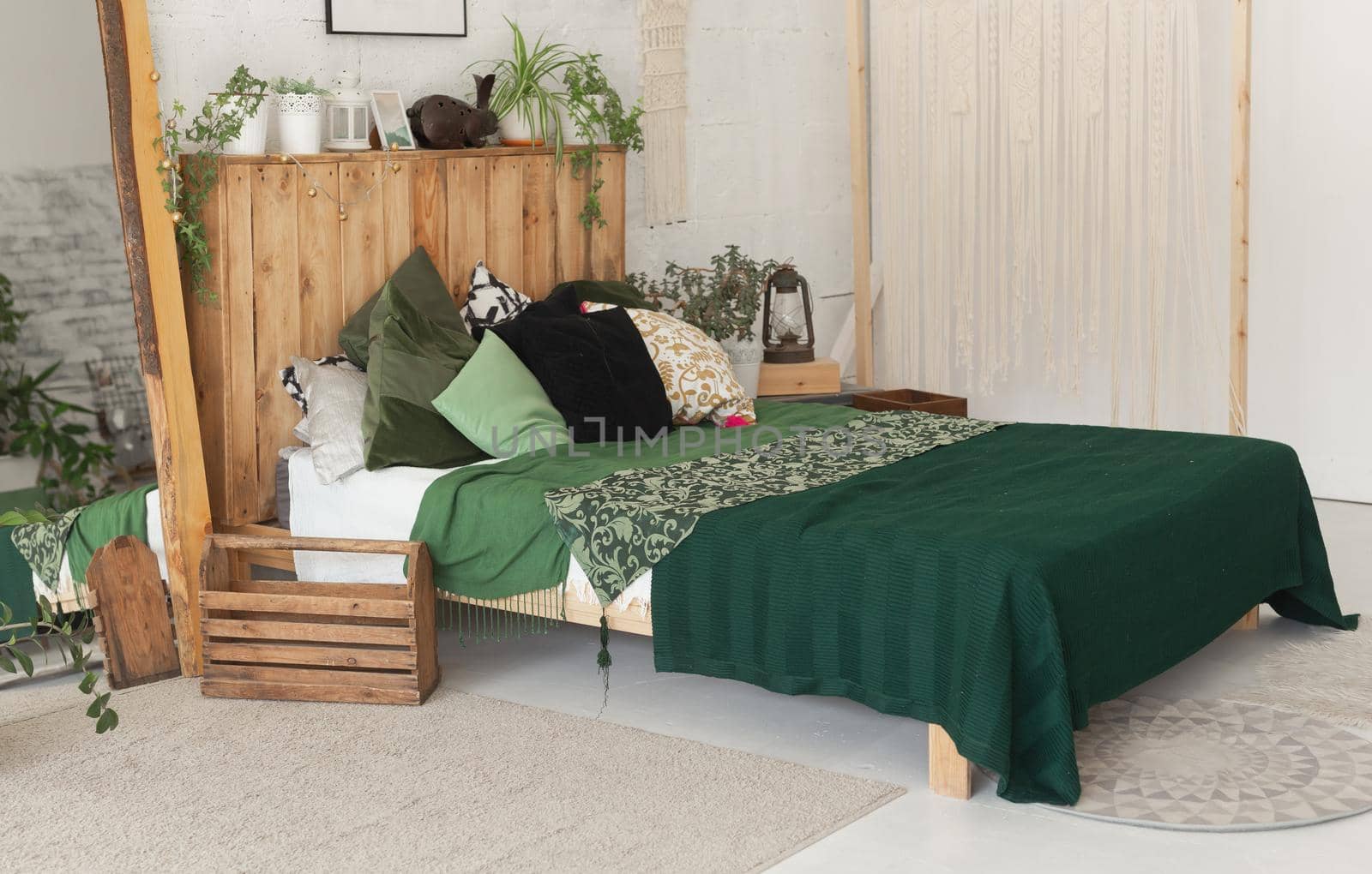 Comfortable bed with new green linens in eco style room interior.