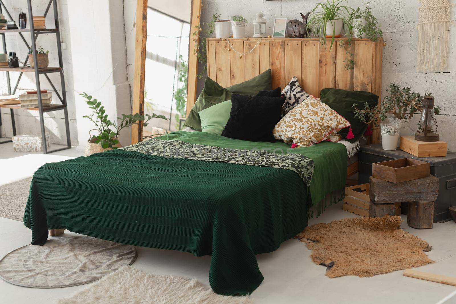 Comfortable bed with new green linens in eco style room interior.