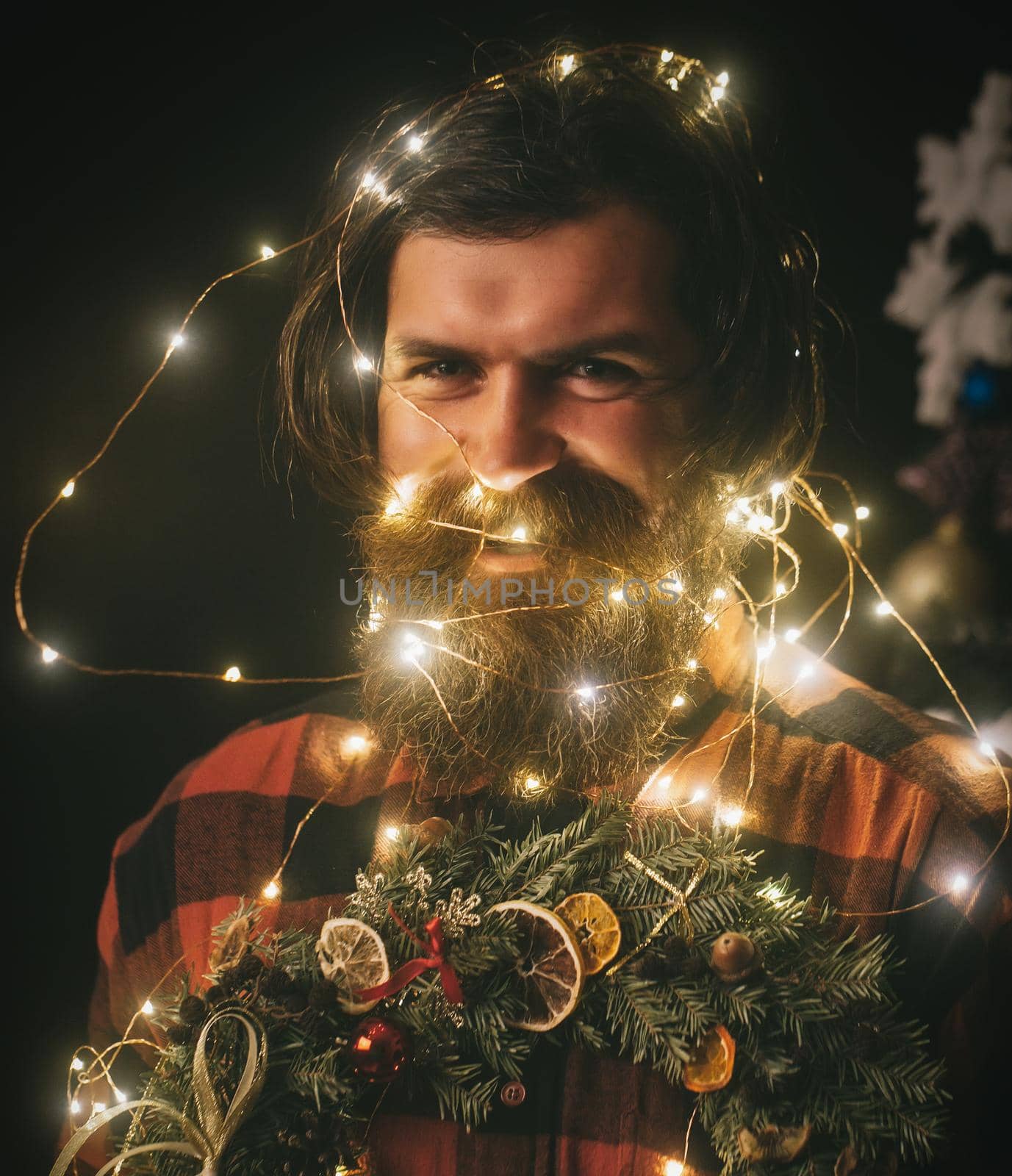 Christmas man with beard on happy face and garland. Garland on santa claus man as decoration hold wreath.
