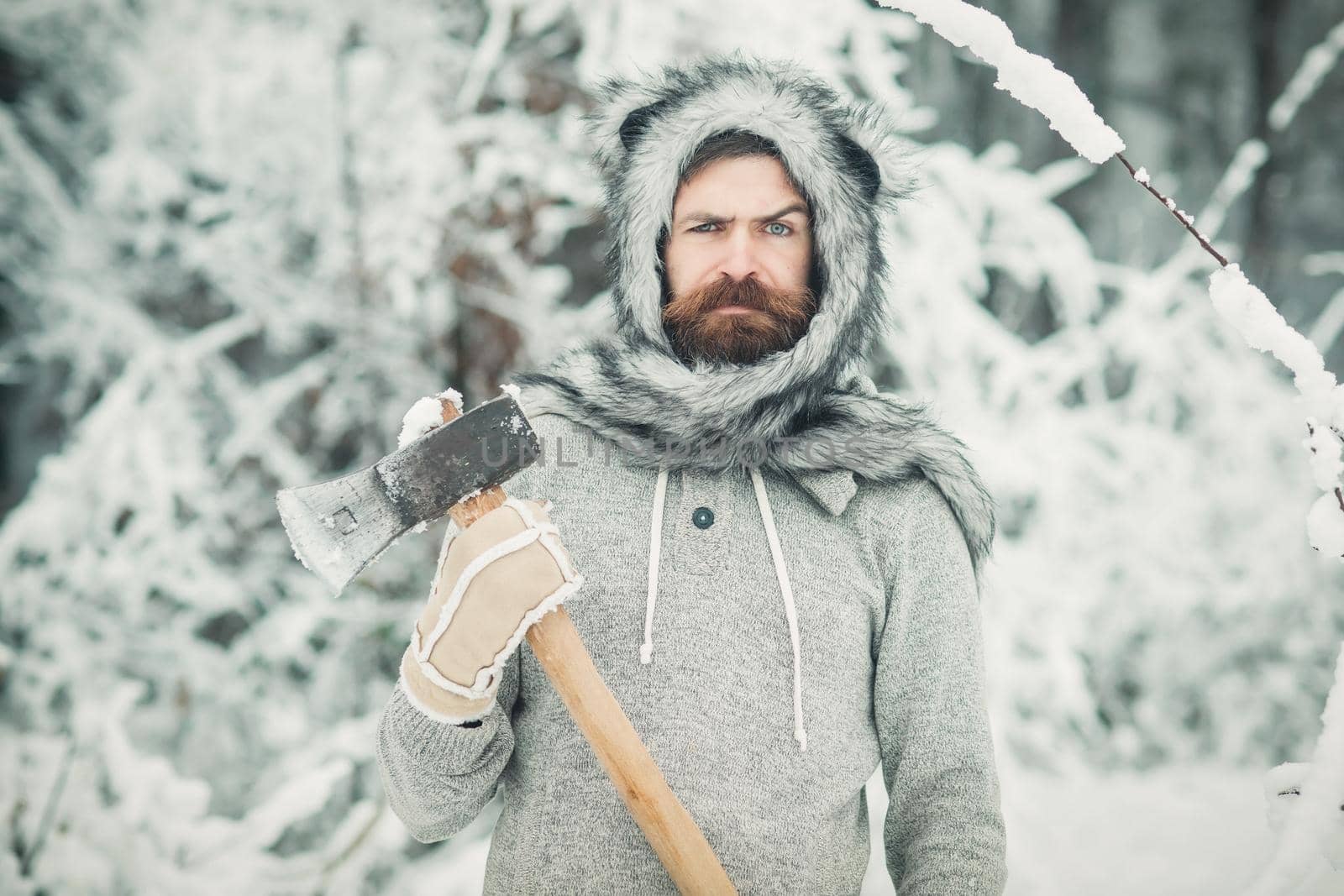 Winter bearded man lumberjack hold axe in snowy winter forest