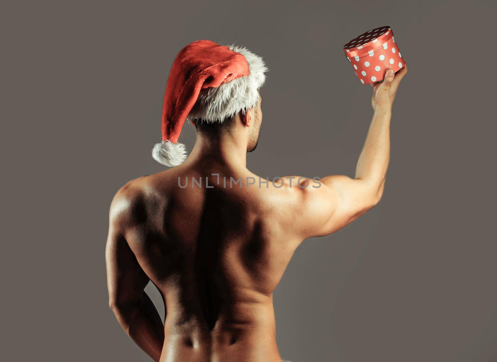 Sexy santa gay. Muscular christmas man in hat or naked sexy athletic body, standing with back. Sexy santa.