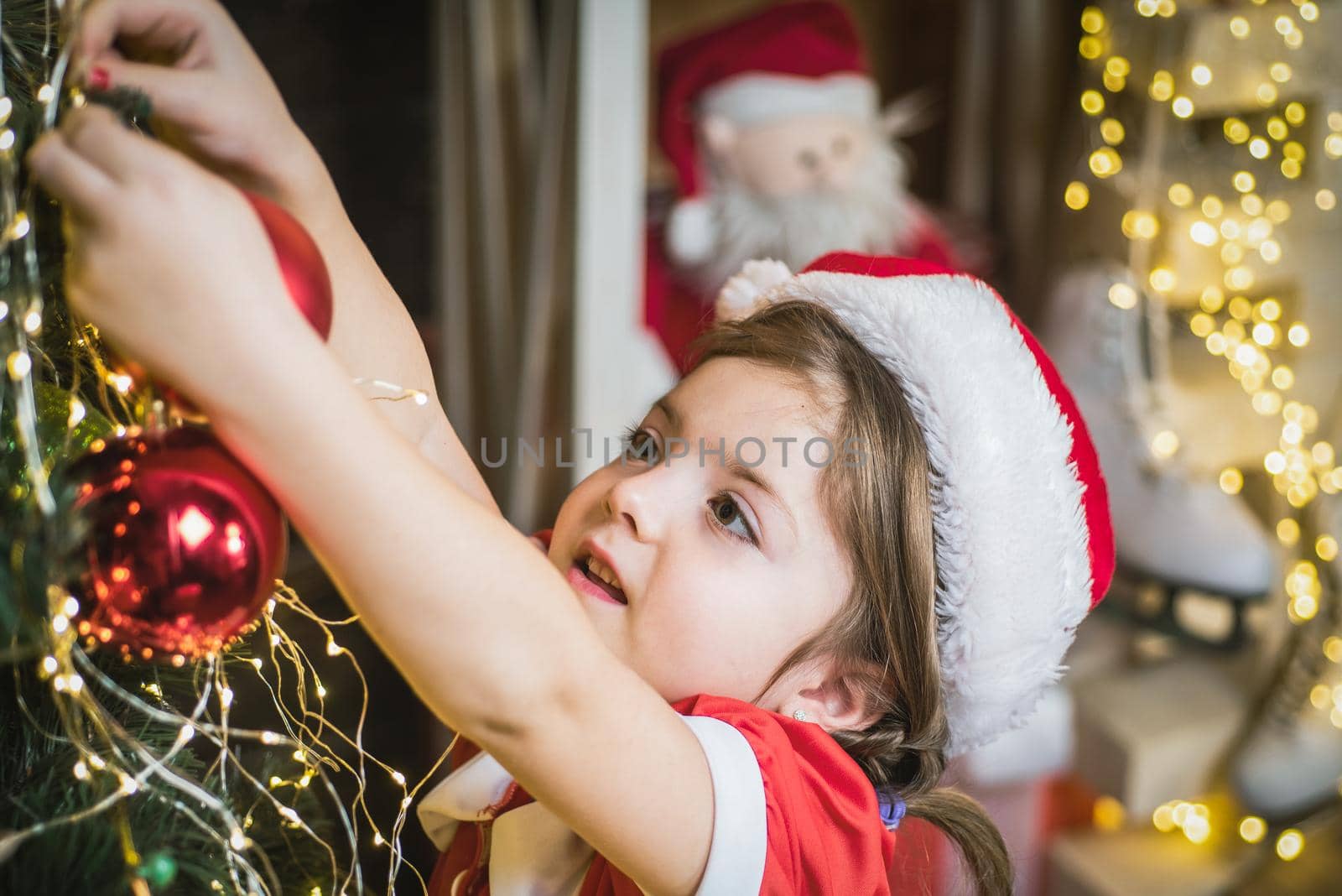 Christmas kid girl decorating Christmas tree at home