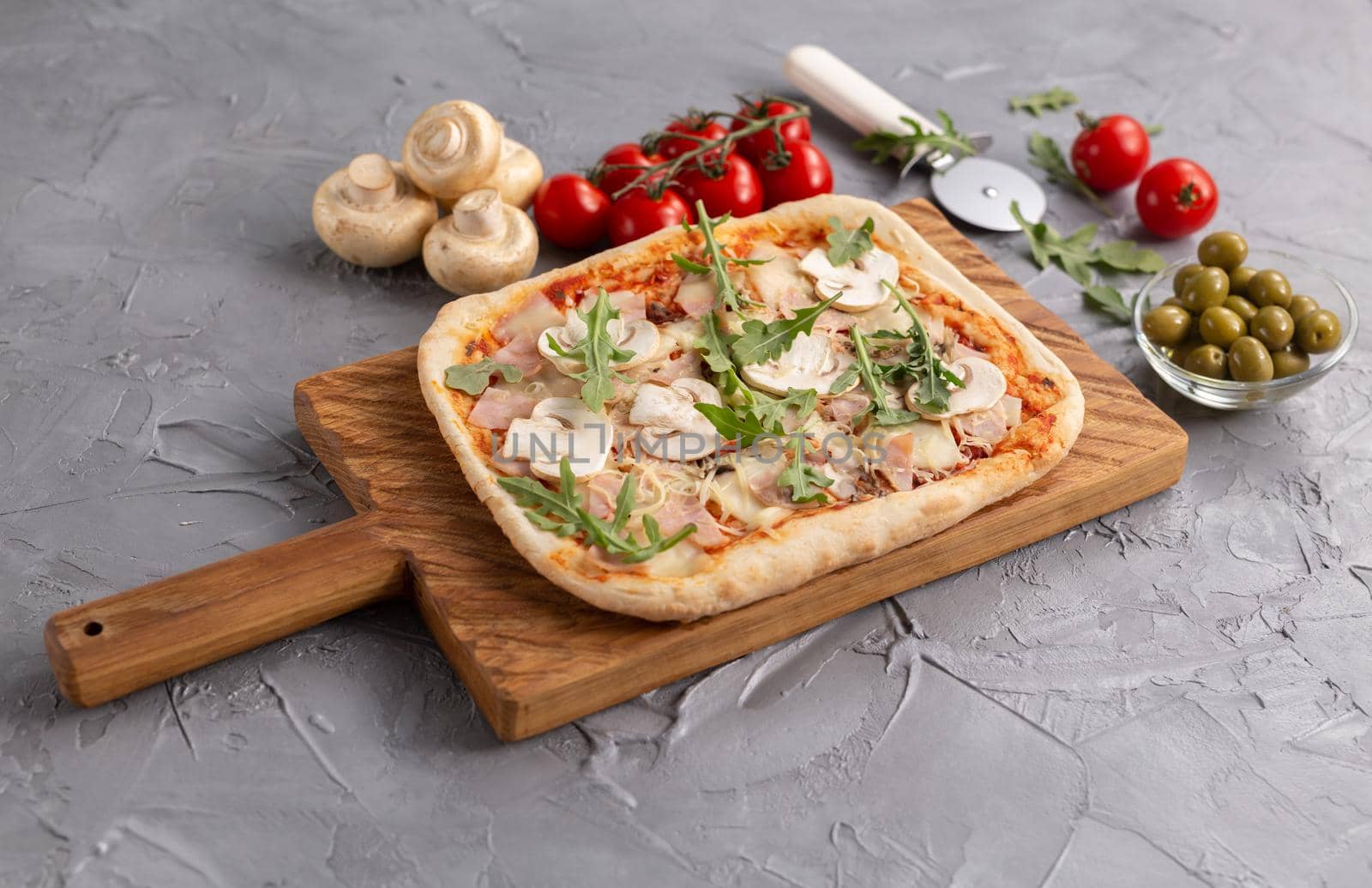 Rectangular pizza with mushrooms, tomatoes and arugula on a wooden cutting board by Satura86