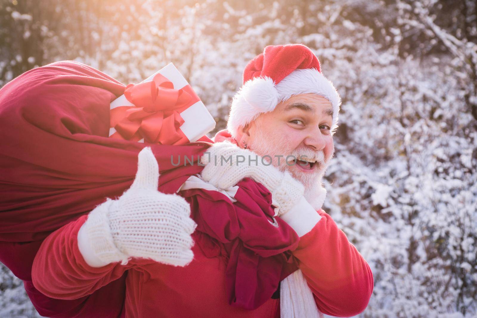 Santa Claus comes with thumb up in the snow forest, senior thumbs up sign. by Tverdokhlib