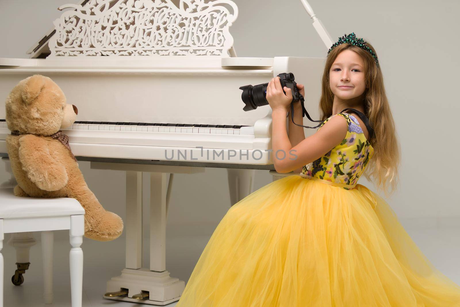 Beautiful little girl photographs a teddy bear in the studio.