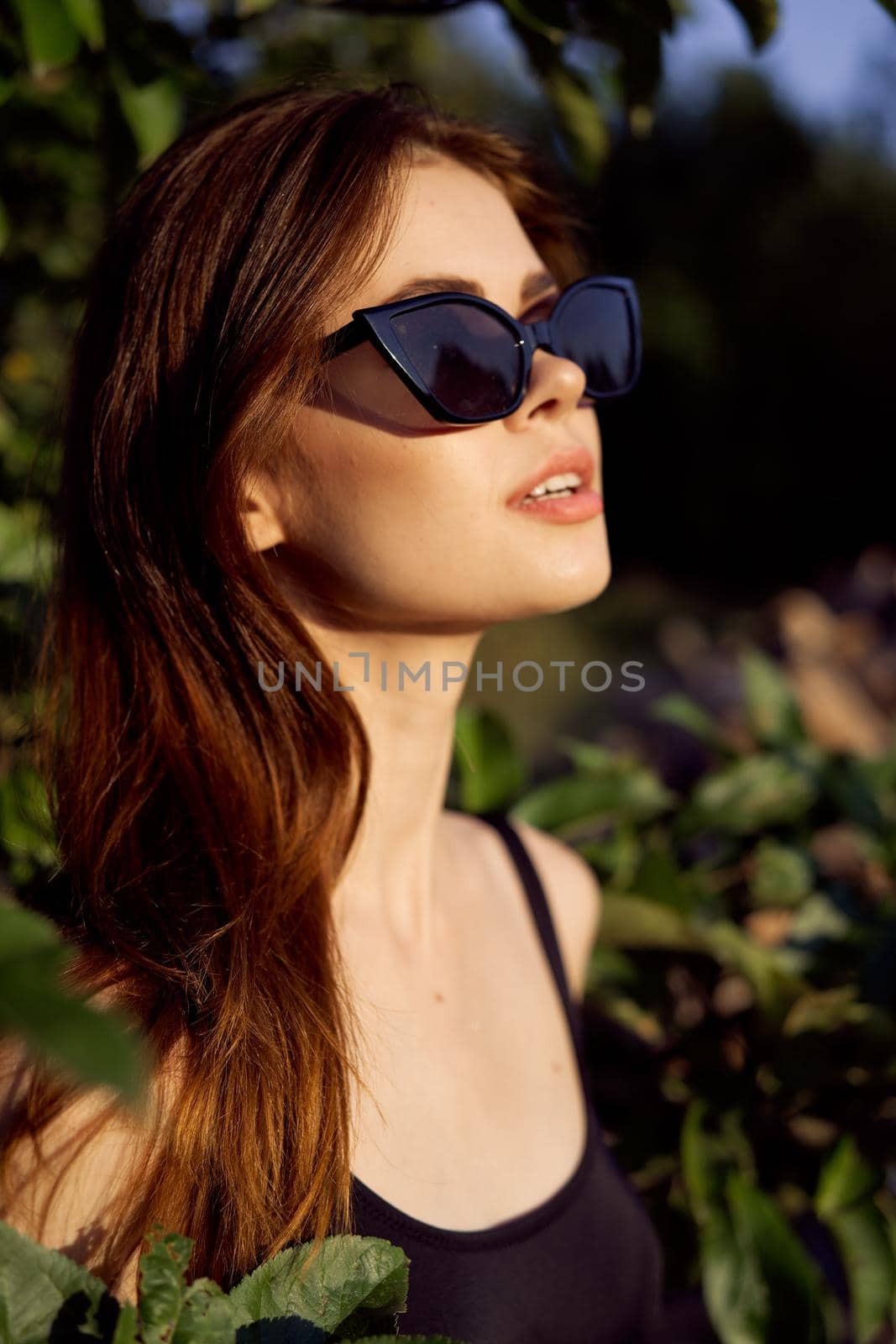 pretty woman in sunglasses in summer outdoors green leaves. High quality photo