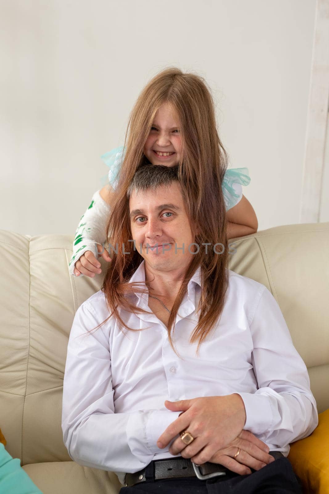 Father and his daughter having fun in their living room. Little girl have injury hand but she is happy be together her dad