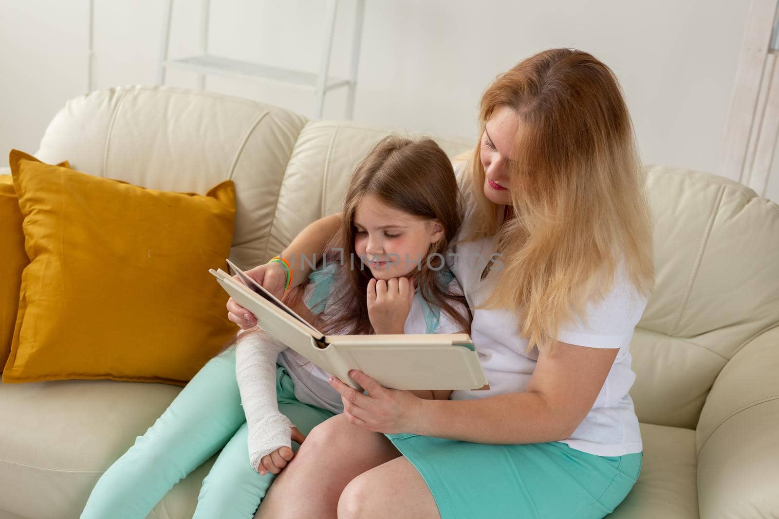 Child with broken arm and gypsum spend time at home with mother. Childhood illnesses, a positive outlook and recovery