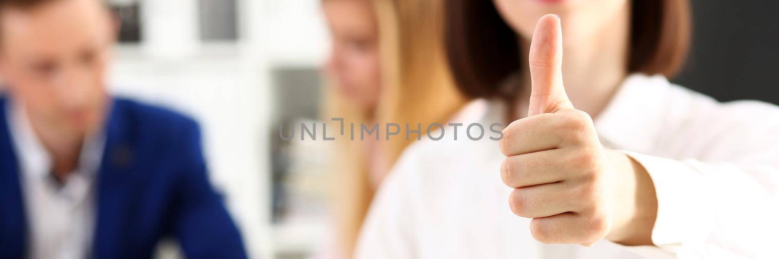 Female arm show OK or approval with thumb up in creative people office closeup. High level quality product, serious offer conference, mediation solution, advisor participation concept