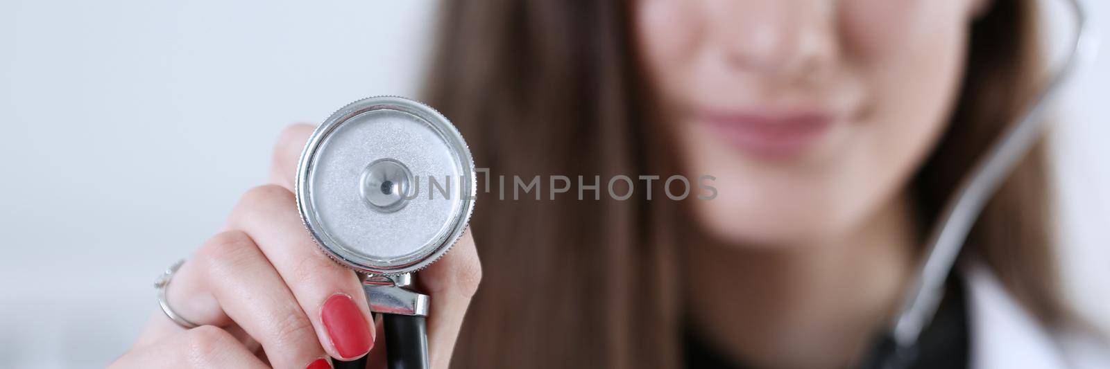 Female medicine doctor hand holding stethoscope head closeup in front of her chest. Medic shop or store, physical and disease prevention, er consultant, 911, pulse measure, healthy lifestyle concept