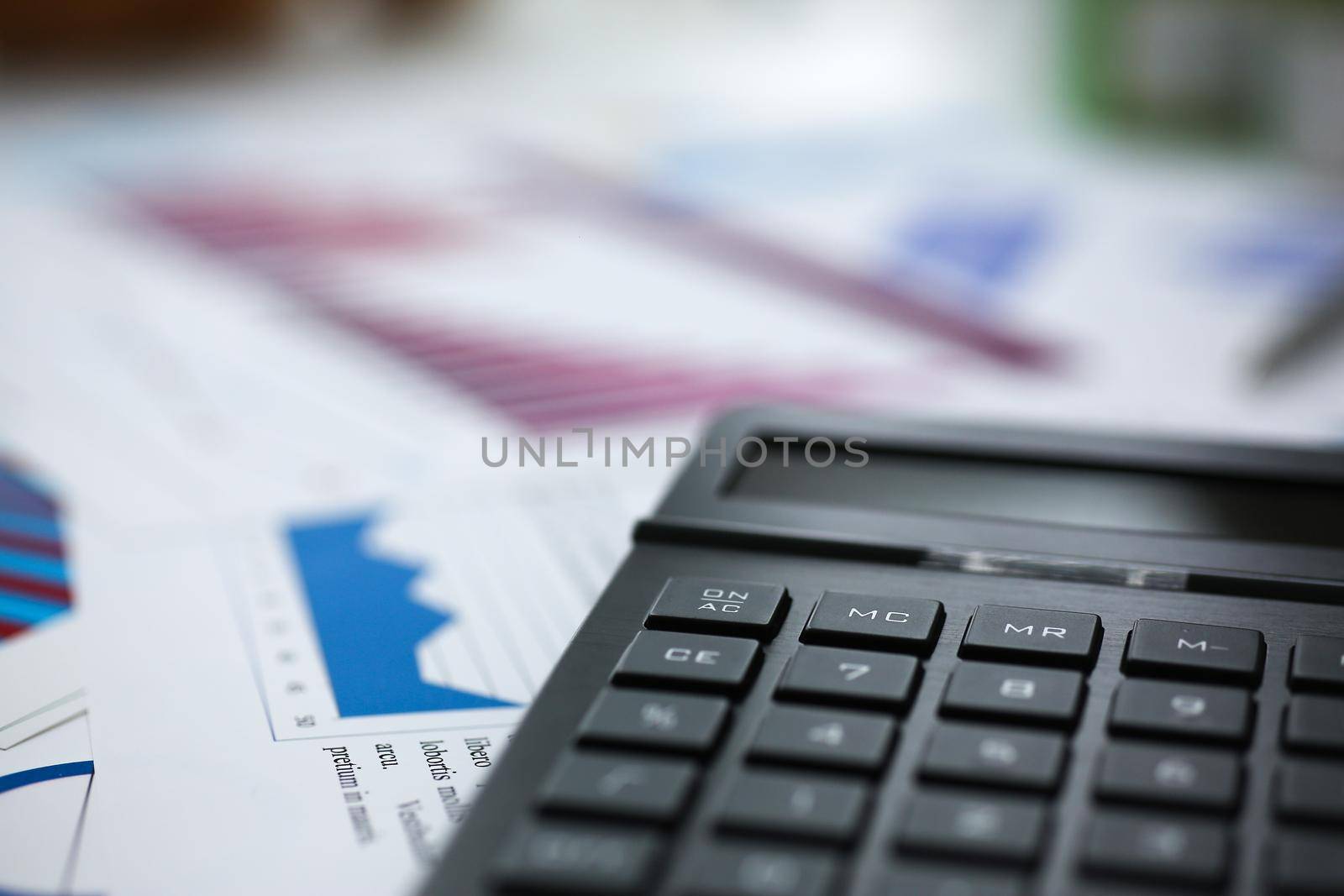 Black calculator and financial statistics on infographics at office table closeup. Internal Revenue Service inspector sum check, irs investigation, earnings, savings, loan and credit concept