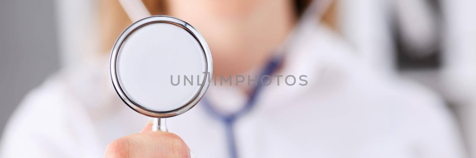 Female medicine doctor hand holding stethoscope head closeup in front of her chest. Medic shop or store, physical and disease prevention, er consultant, 911, pulse measure, healthy lifestyle concept
