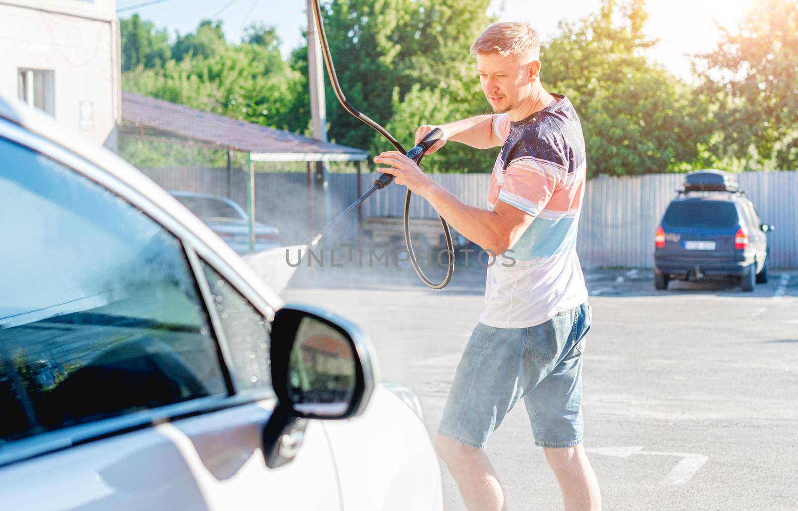 Man is washing car with high pressure water