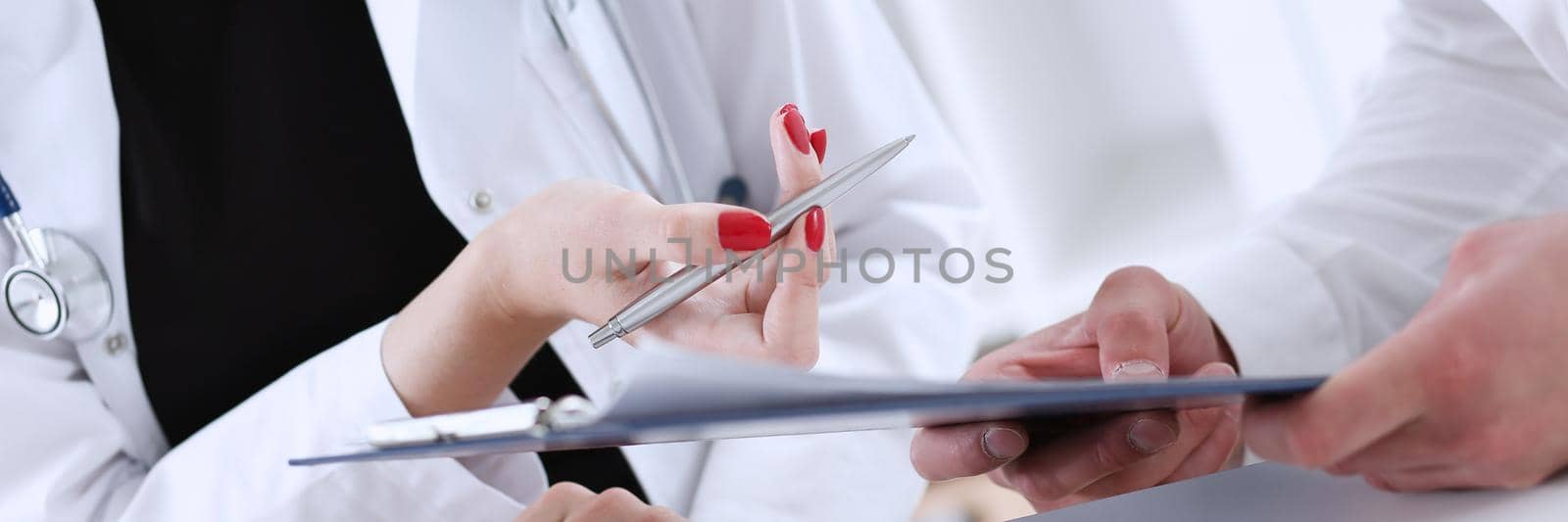 Female doctor hand hold silver pen and showing pad. Physical agreement form signature, disease prevention, ward round reception, consent contract sign, prescribe remedy, healthy lifestyle concept
