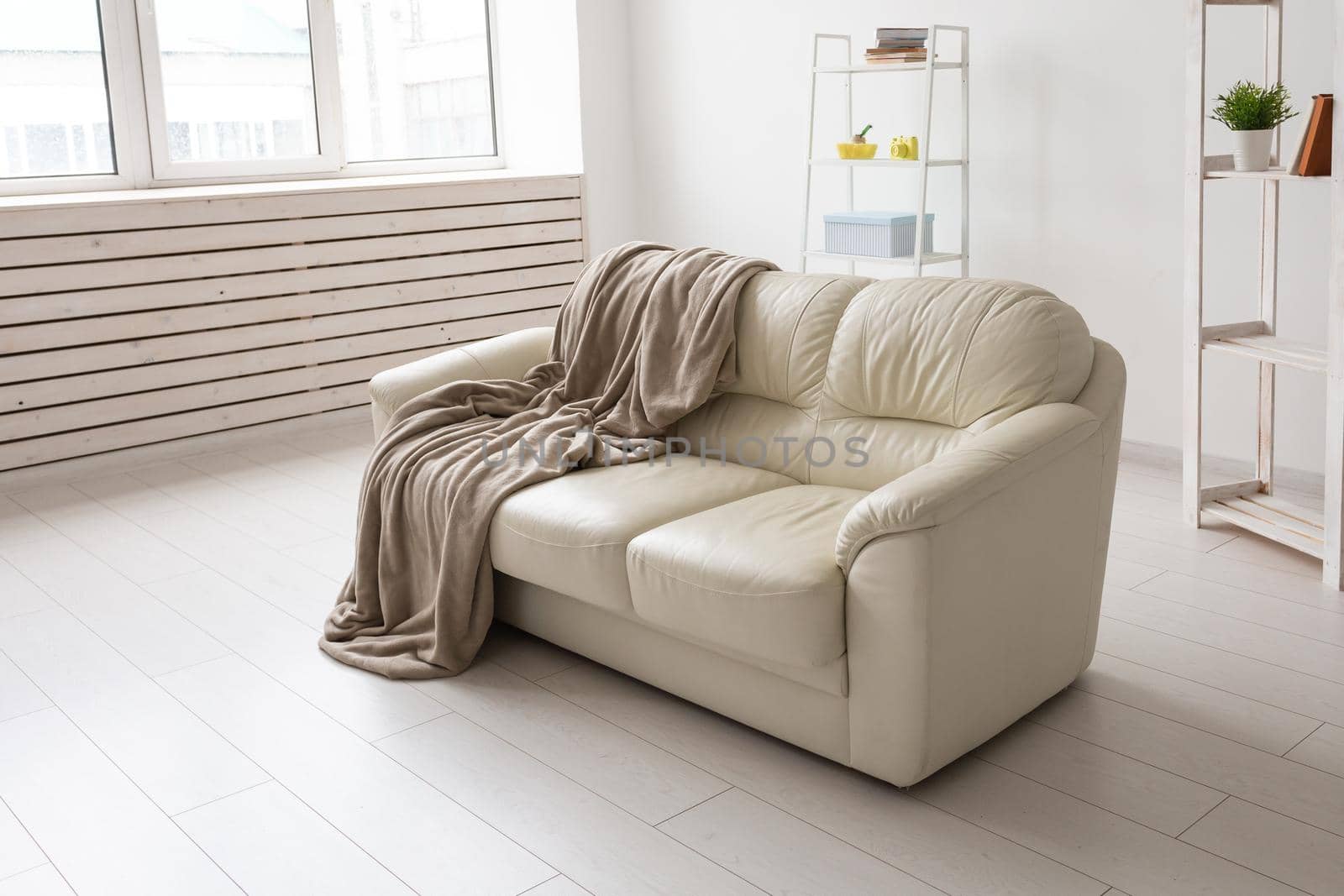 Beige sofa against white empty wall in simple living room interior. Minimalism concept