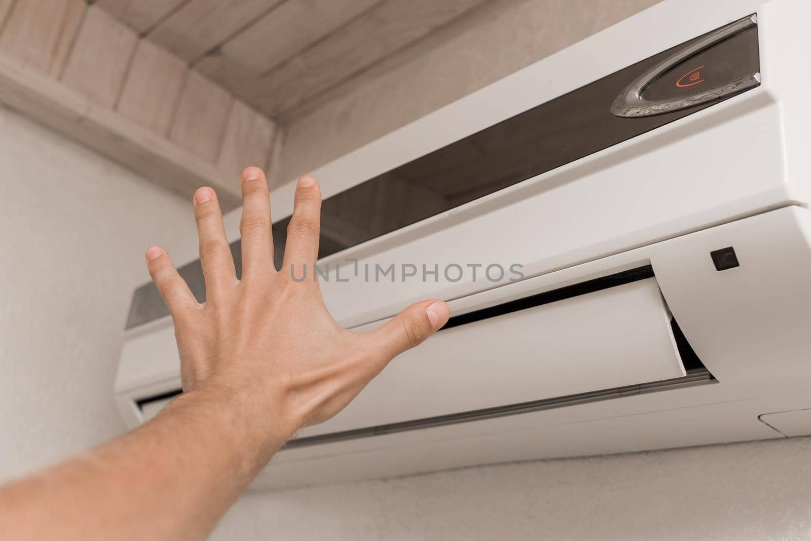 The guy puts his hand under the air conditioner in the room to check the temperature and the feeling of warm or cold air by AYDO8