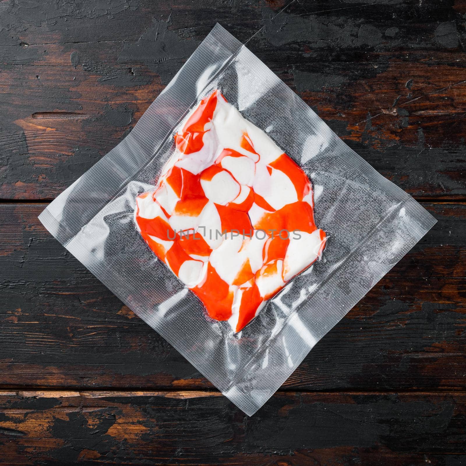 Surimi vacuum pack, on dark wooden background, top view flat lay by Ilianesolenyi